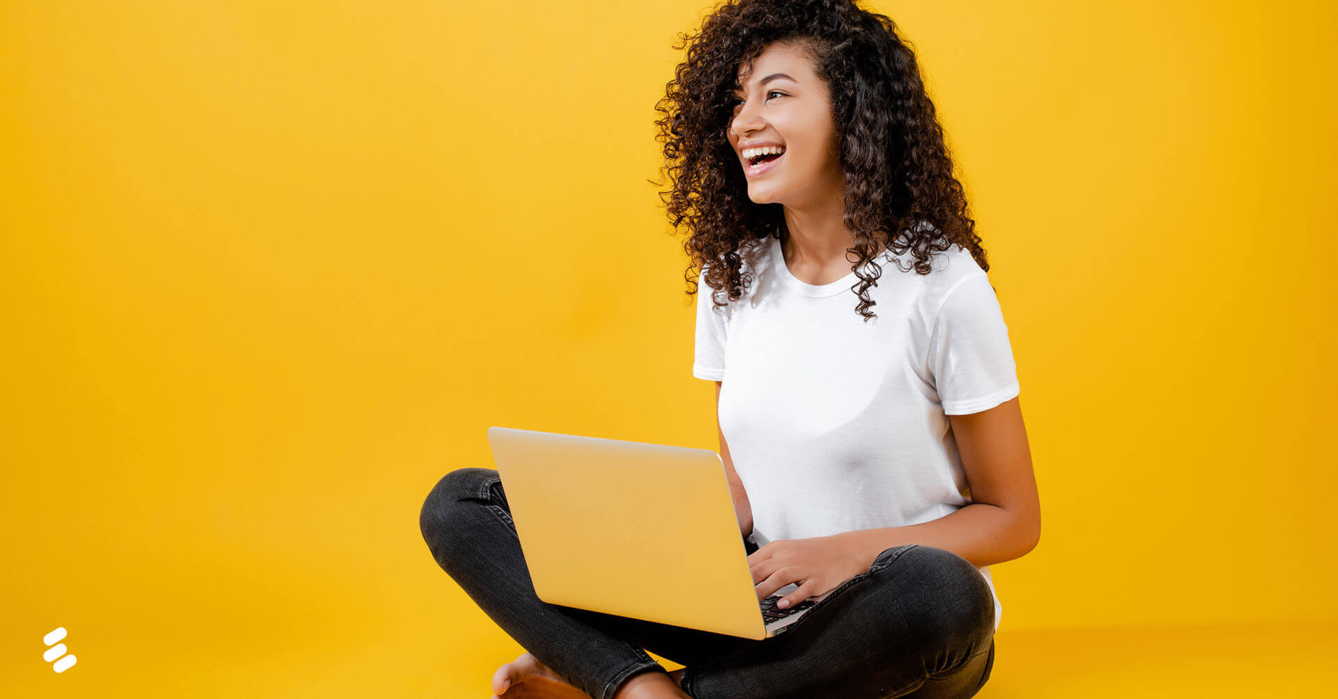 A young woman uses a laptop while sitting on the floor.