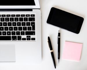 A computer and phone on a desk.